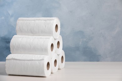 Photo of Many rolls of paper towels on white wooden table. Space for text