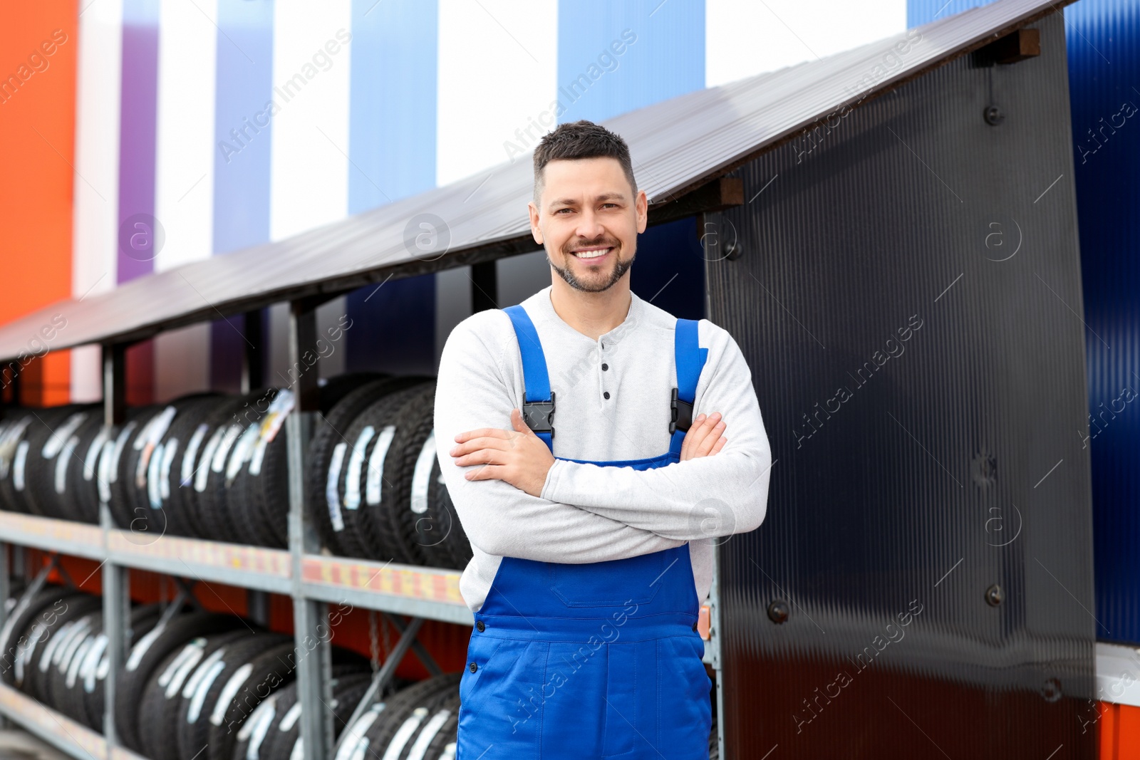 Photo of Mechanic near rack with car tires at service station