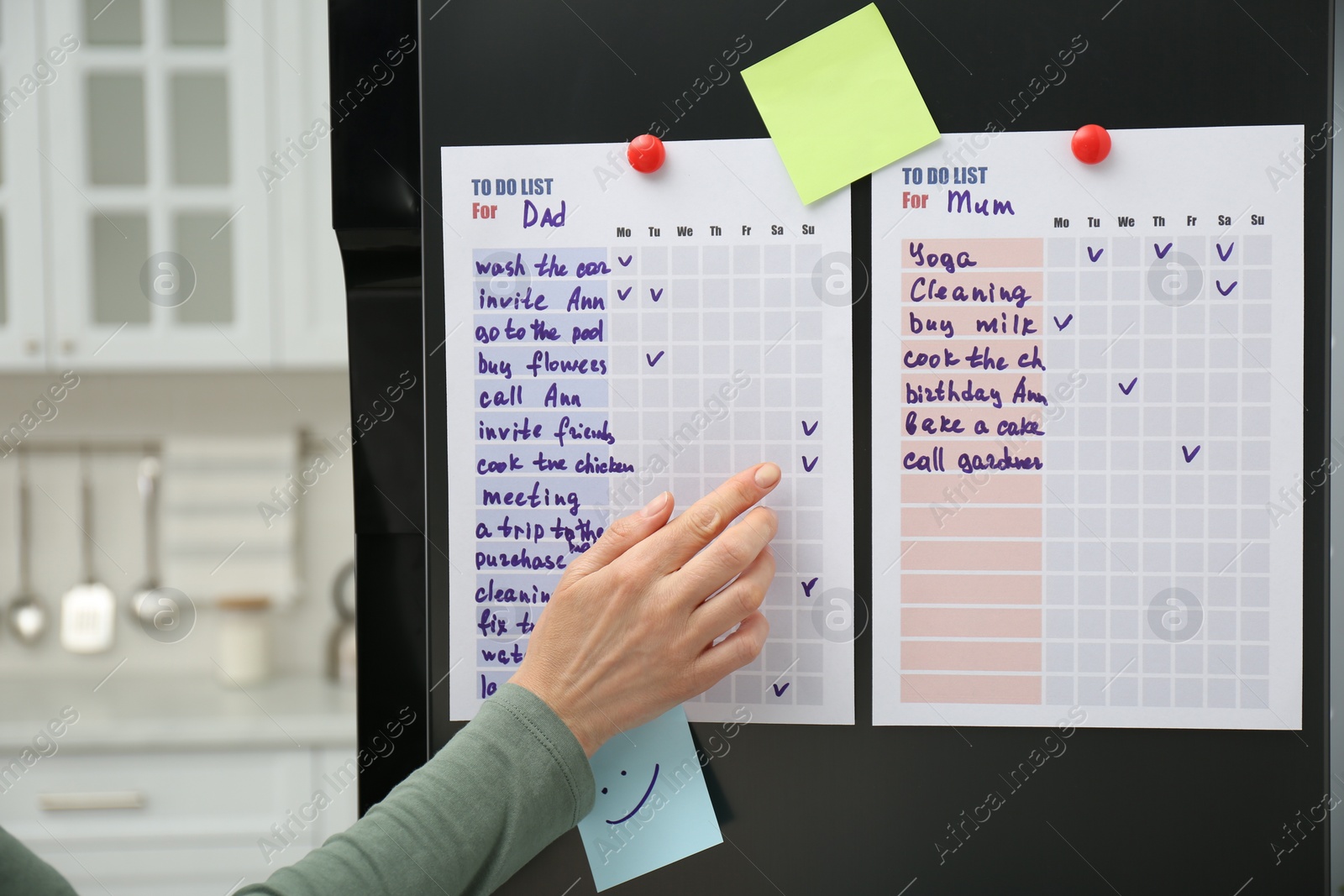 Photo of Woman checking to do list on fridge in kitchen, closeup