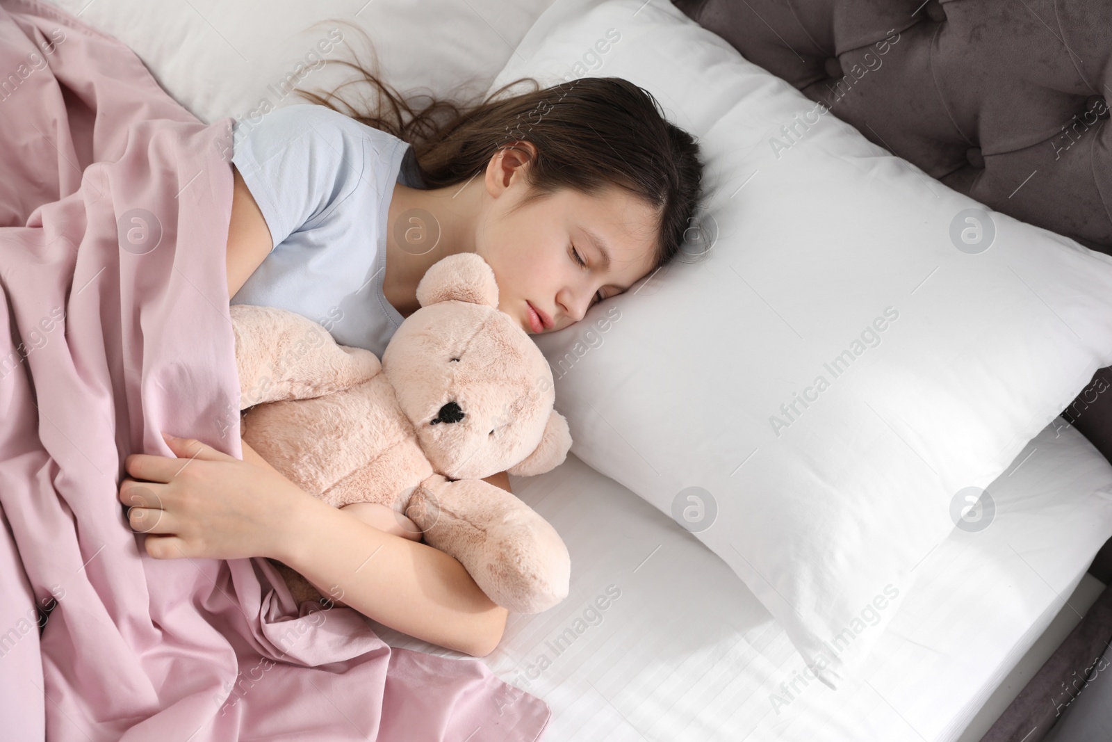 Photo of Beautiful little girl with teddy bear sleeping in bed