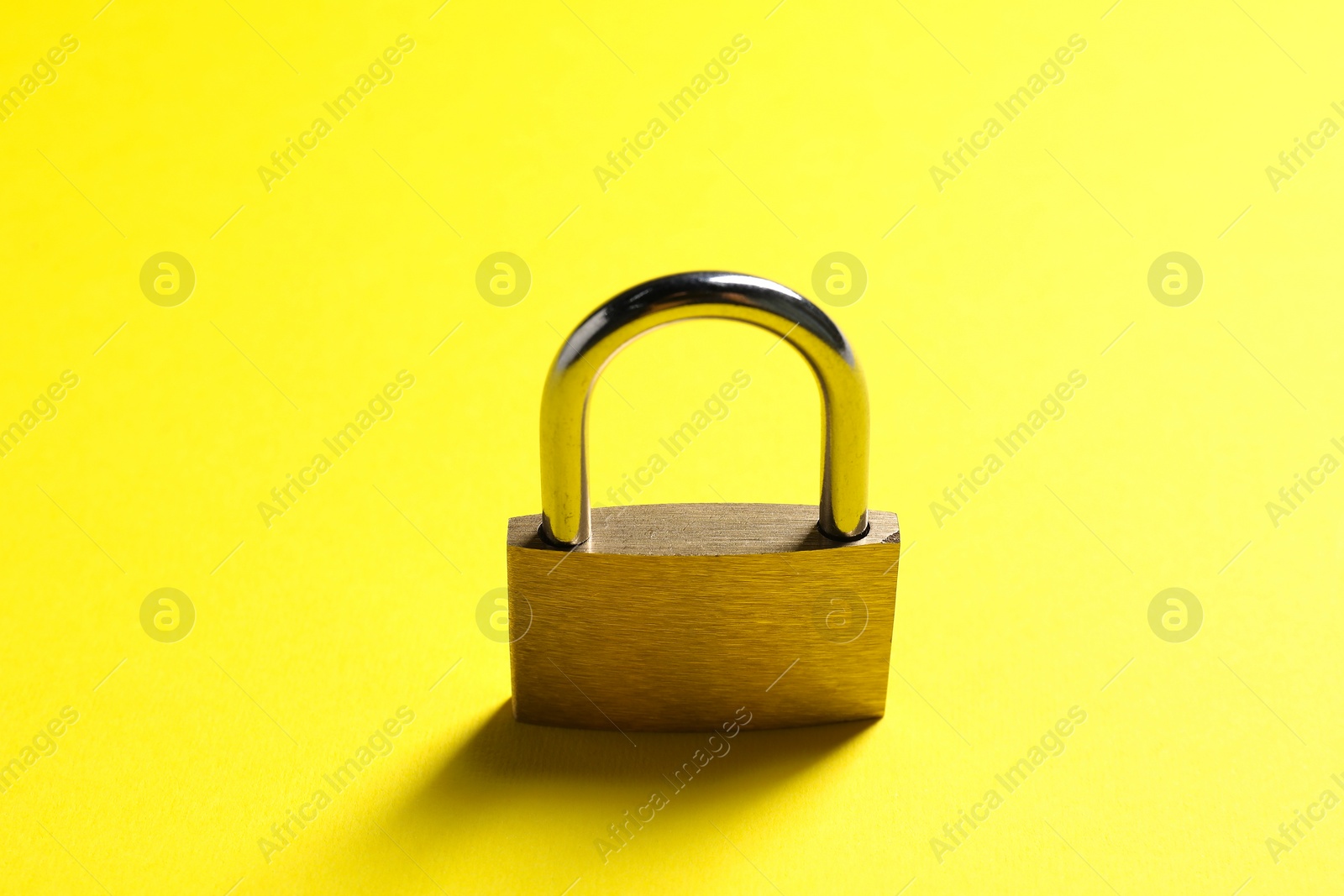 Photo of One locked steel padlock on yellow background