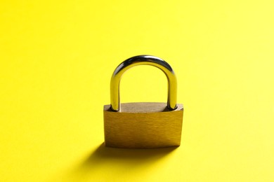 Photo of One locked steel padlock on yellow background