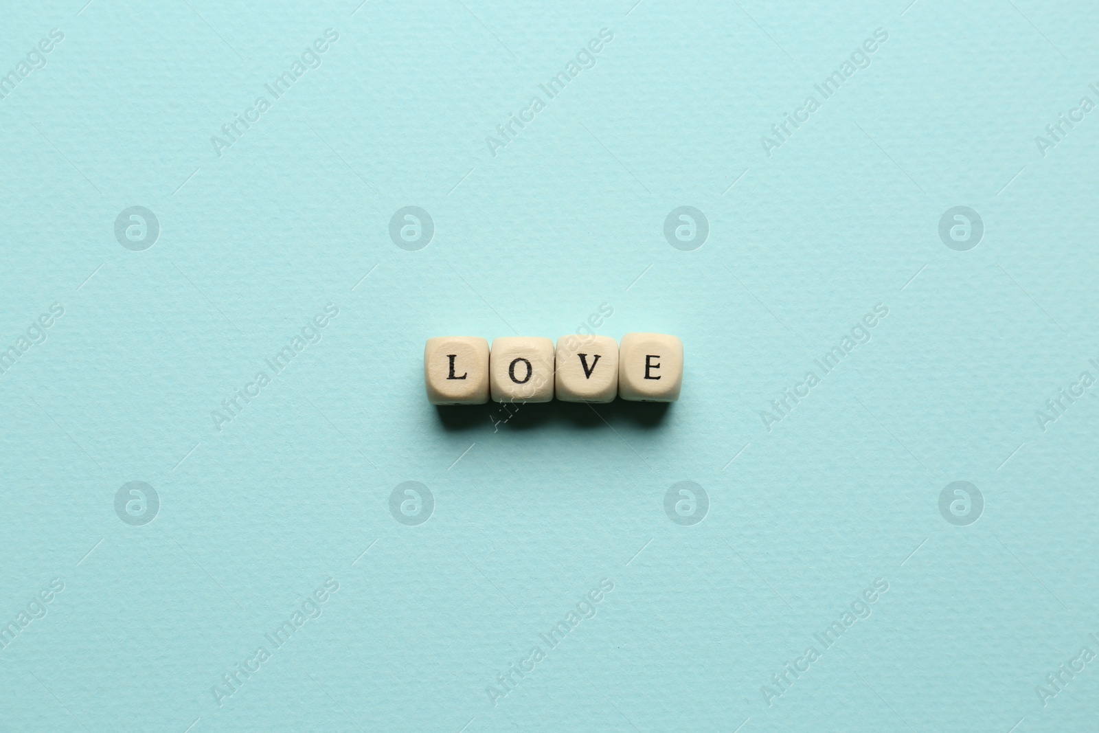 Photo of Mini cubes with letters forming word Love on light blue background, flat lay