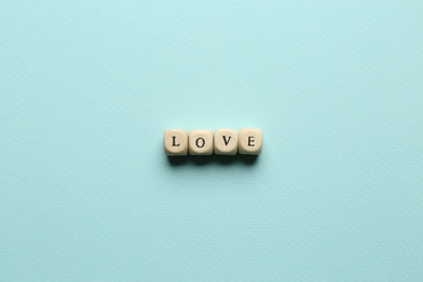 Photo of Mini cubes with letters forming word Love on light blue background, flat lay