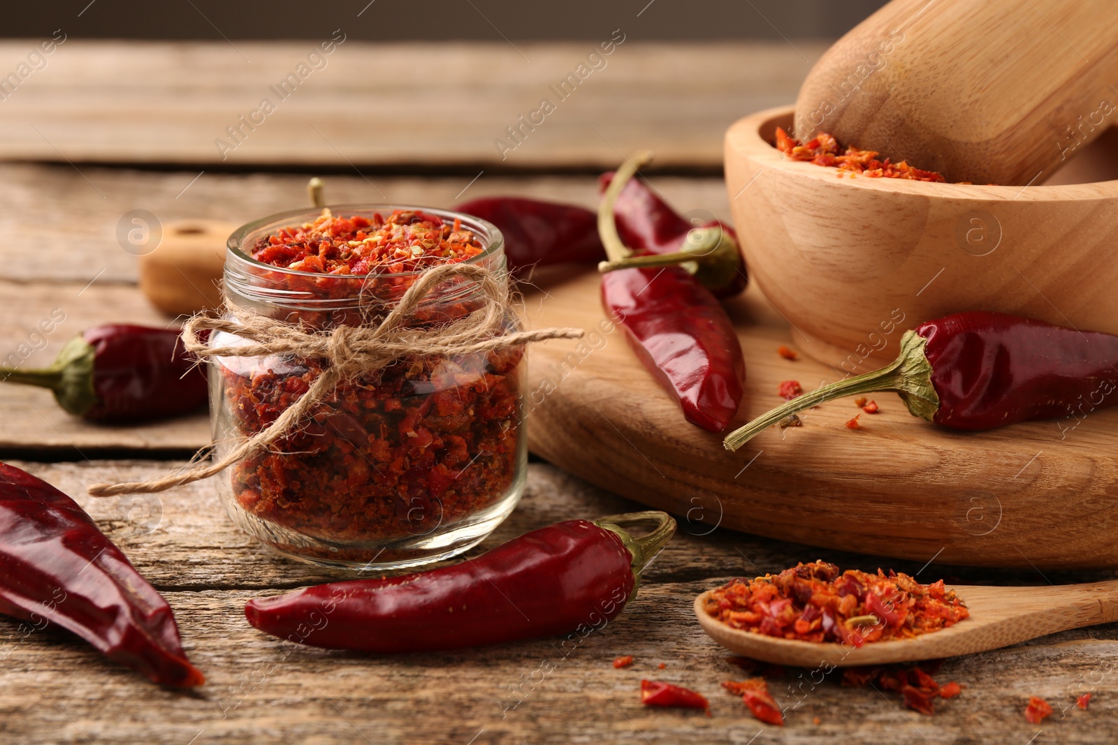 Photo of Chili pepper flakes and pods on wooden table, closeup