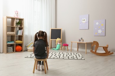 Photo of Lonely little girl at home, back view. Autism concept