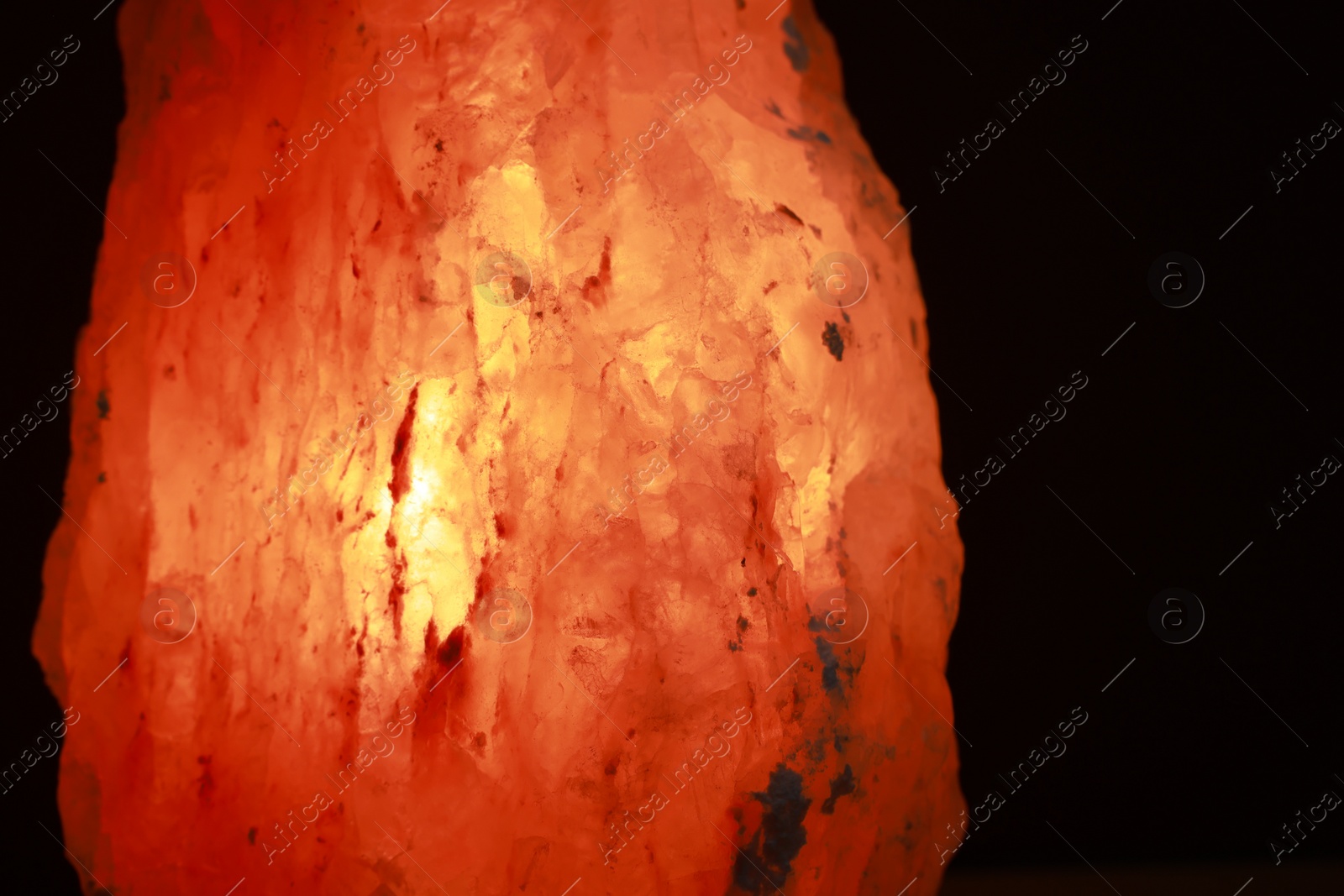 Photo of Himalayan salt lamp on dark background, closeup