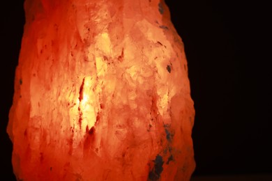 Photo of Himalayan salt lamp on dark background, closeup