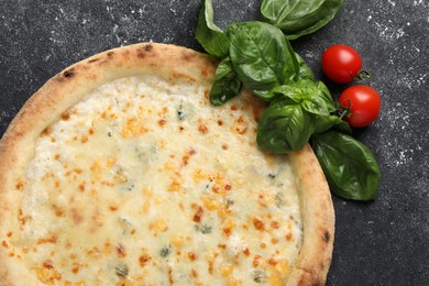 Delicious cheese pizza, basil and tomatoes on black textured table, flat lay