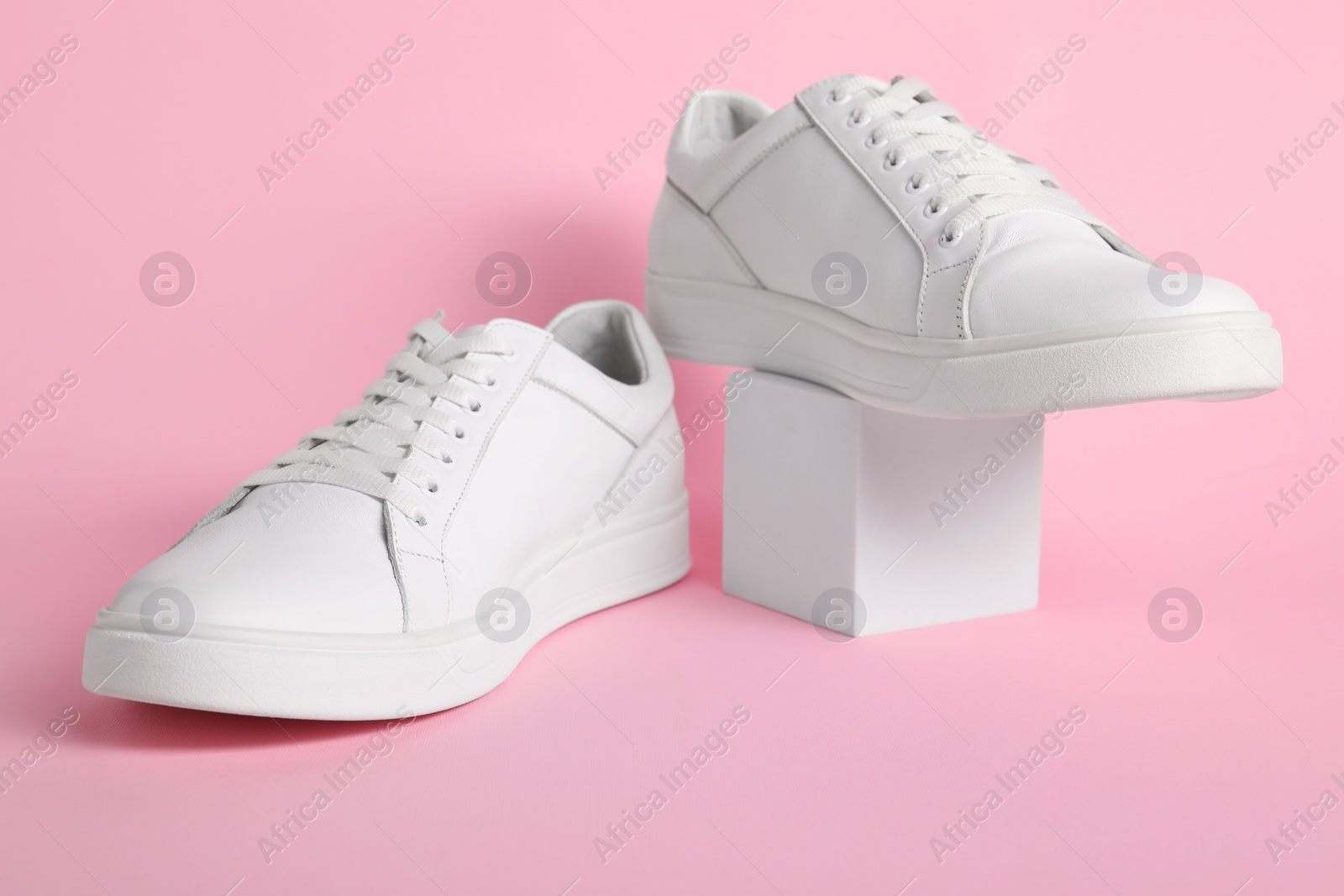 Photo of Pair of stylish white sneakers on pink background