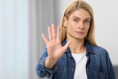 Photo of Woman showing stop gesture in room. Space for text