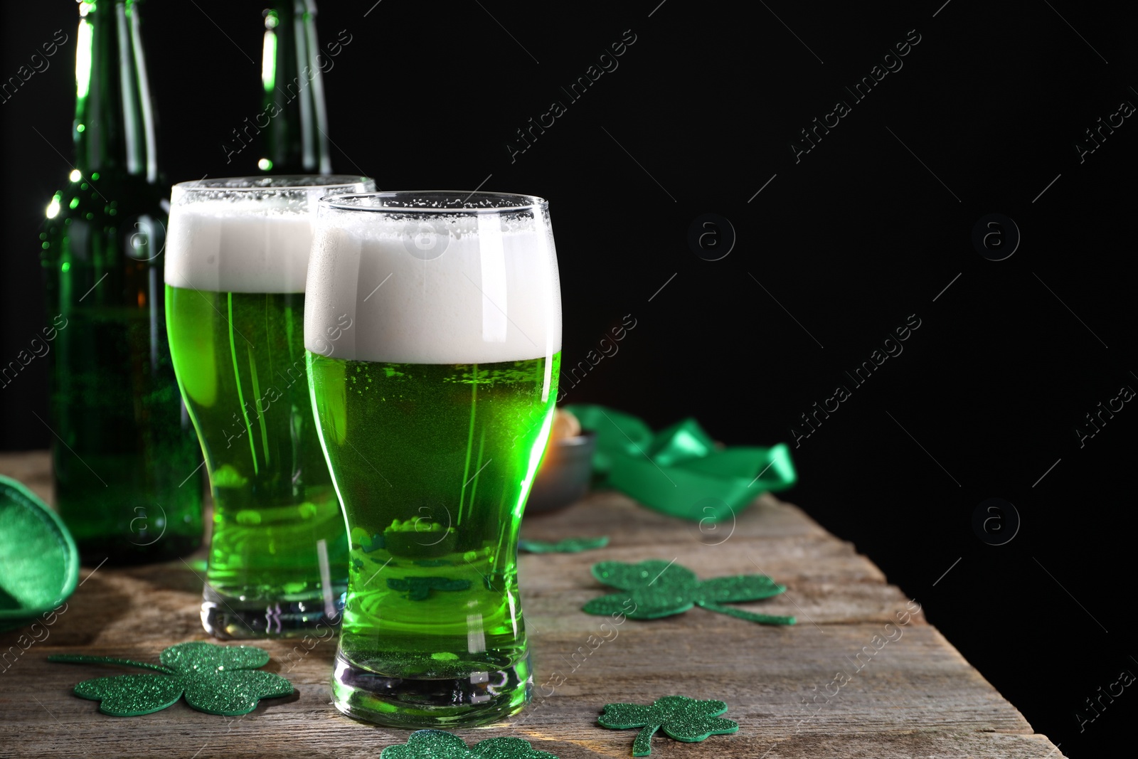 Photo of St. Patrick's day party. Green beer and decorative clover leaves on wooden table. Space for text