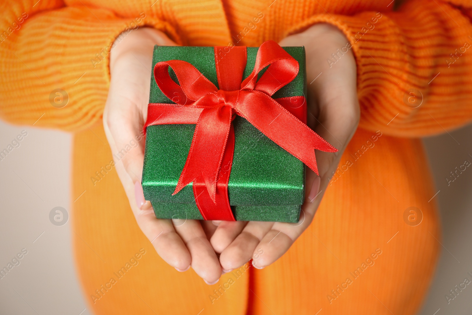 Photo of Christmas present. Woman holding beautifully wrapped gift box on beige background, closeup