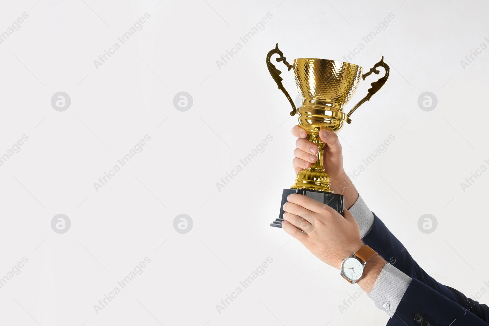 Photo of Businessman holding gold trophy cup on white background, closeup