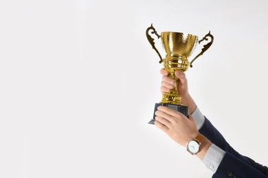 Photo of Businessman holding gold trophy cup on white background, closeup