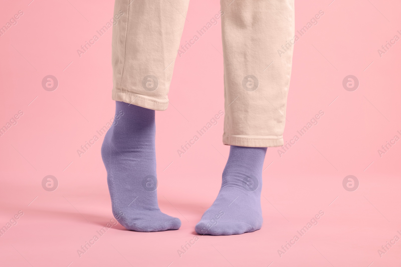 Photo of Woman in stylish purple socks and pants on pink background, closeup