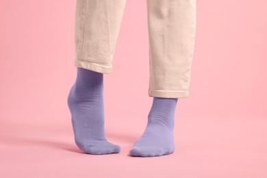 Woman in stylish purple socks and pants on pink background, closeup