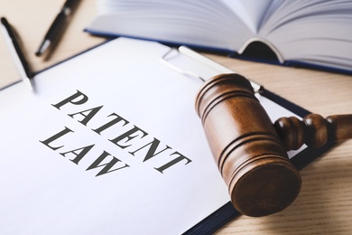 Image of Clipboard with phrase Patent Law and gavel on wooden table, closeup