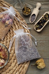 Photo of Scented sachets with dried flowers on wooden table, flat lay