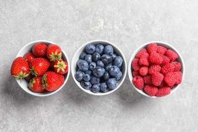 Photo of Bowls with raspberries, strawberries and blueberries on table, top view