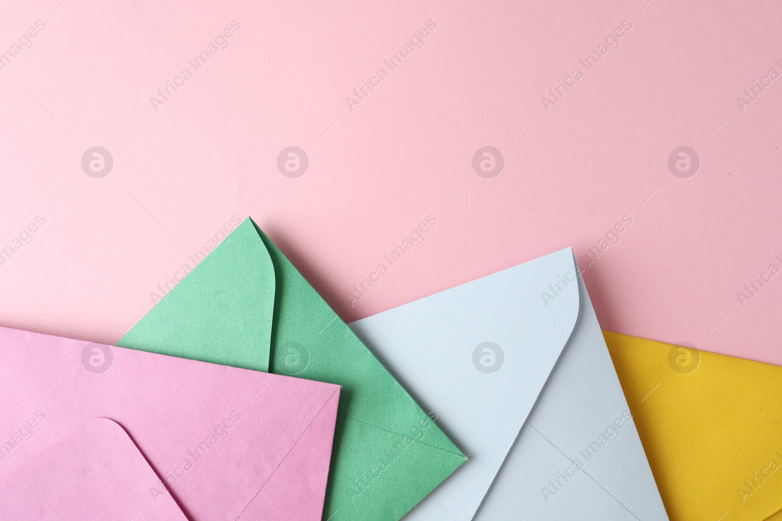 Photo of Colorful paper envelopes on pink background, flat lay. Space for text