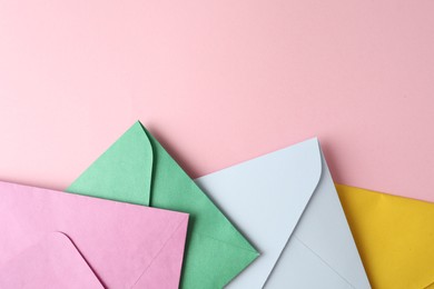 Colorful paper envelopes on pink background, flat lay. Space for text