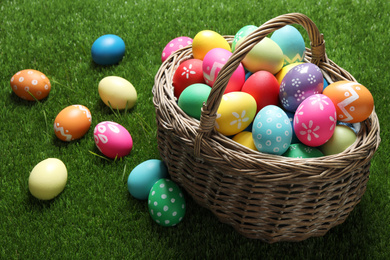 Colorful Easter eggs in basket on green grass