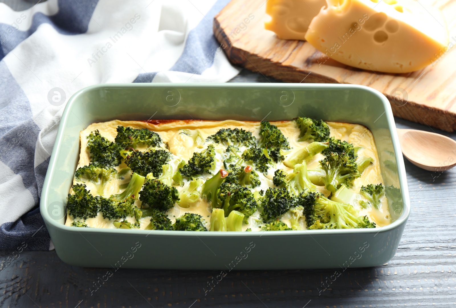 Photo of Tasty broccoli casserole in baking dish on wooden table