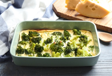 Photo of Tasty broccoli casserole in baking dish on wooden table