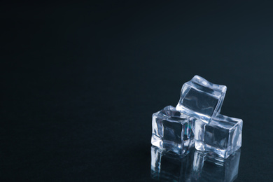 Photo of Crystal clear ice cubes on black background. Space for text