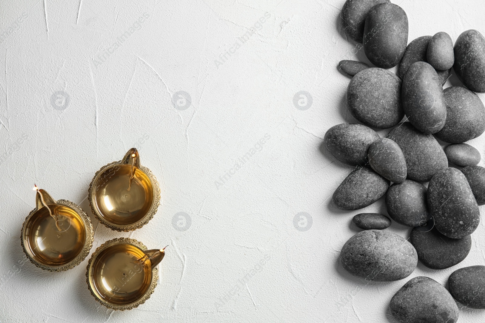 Photo of Zen stones and oil lamps on light background, top view with space for text