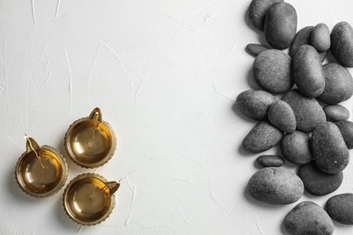 Zen stones and oil lamps on light background, top view with space for text