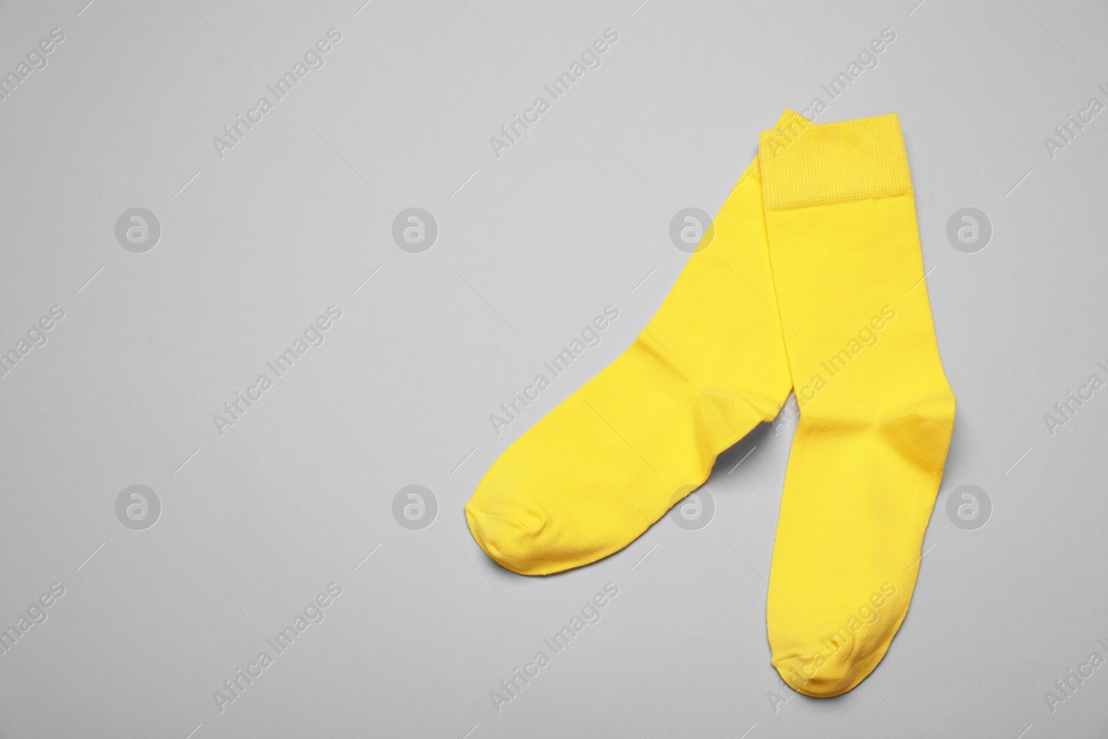 Photo of Yellow socks on grey background, flat lay. Space for text