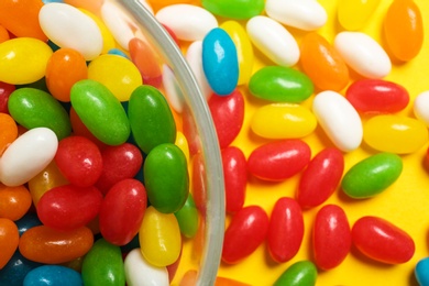 Photo of Bowl of jelly beans on color background, closeup