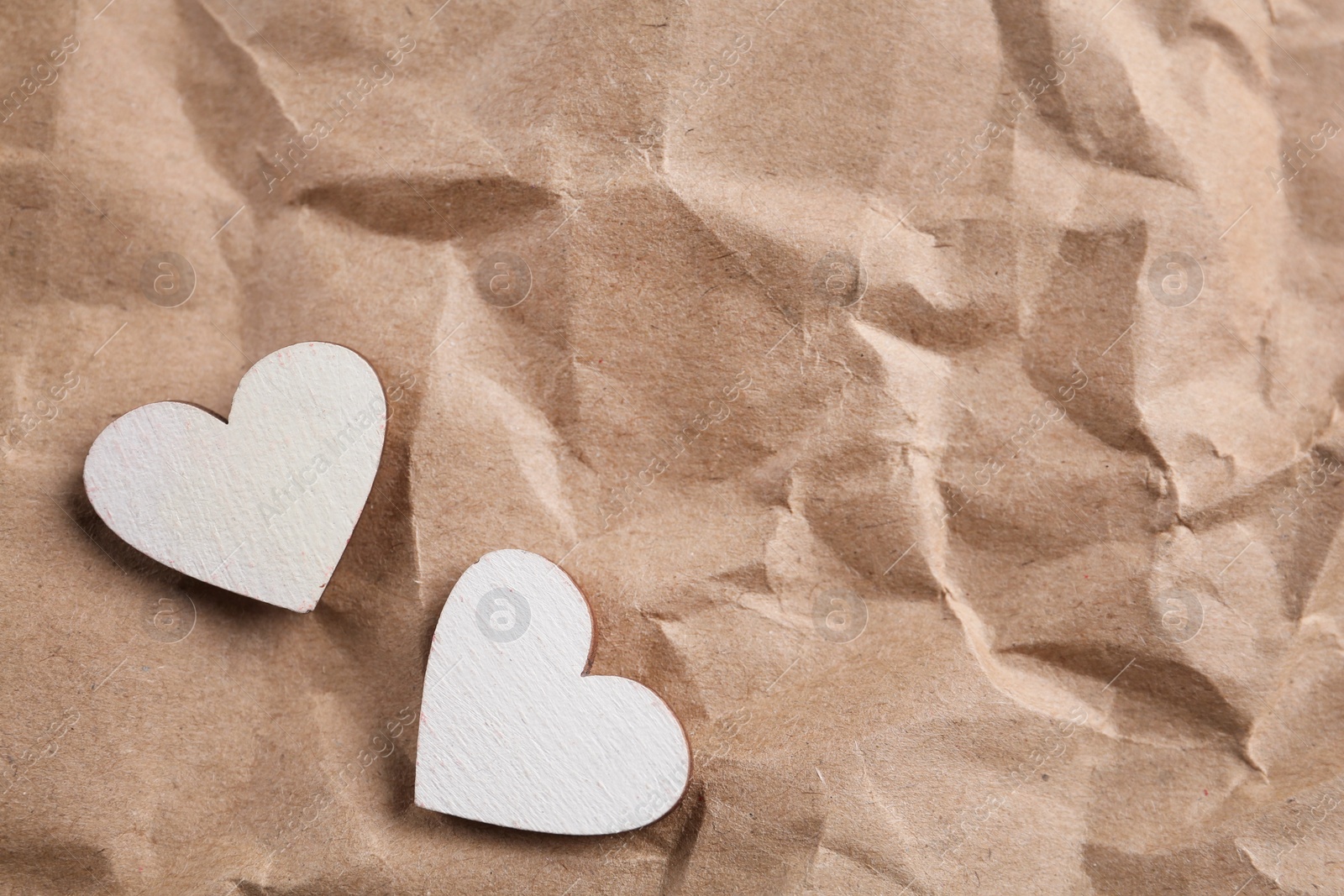 Photo of White wooden hearts on crumpled kraft paper, flat lay with space for text. St. Valentine's day