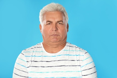 Mature man with double chin on blue background