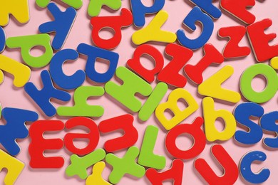 Photo of Learning alphabet. Magnetic letters on pink background, flat lay