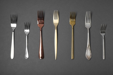 Set of different forks on black background, flat lay