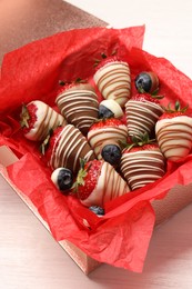 Box with delicious chocolate covered strawberries and blueberries on white table