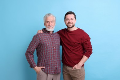 Happy son and his dad on light blue background