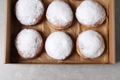 Photo of Delicious buns with powdered sugar in box on light grey table, top view