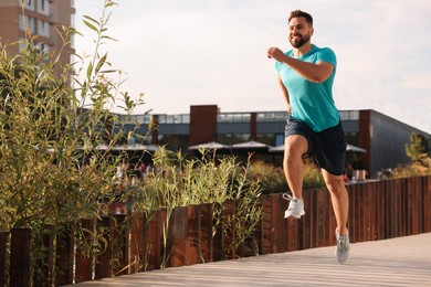 Smiling man running outdoors on sunny day. Space for text