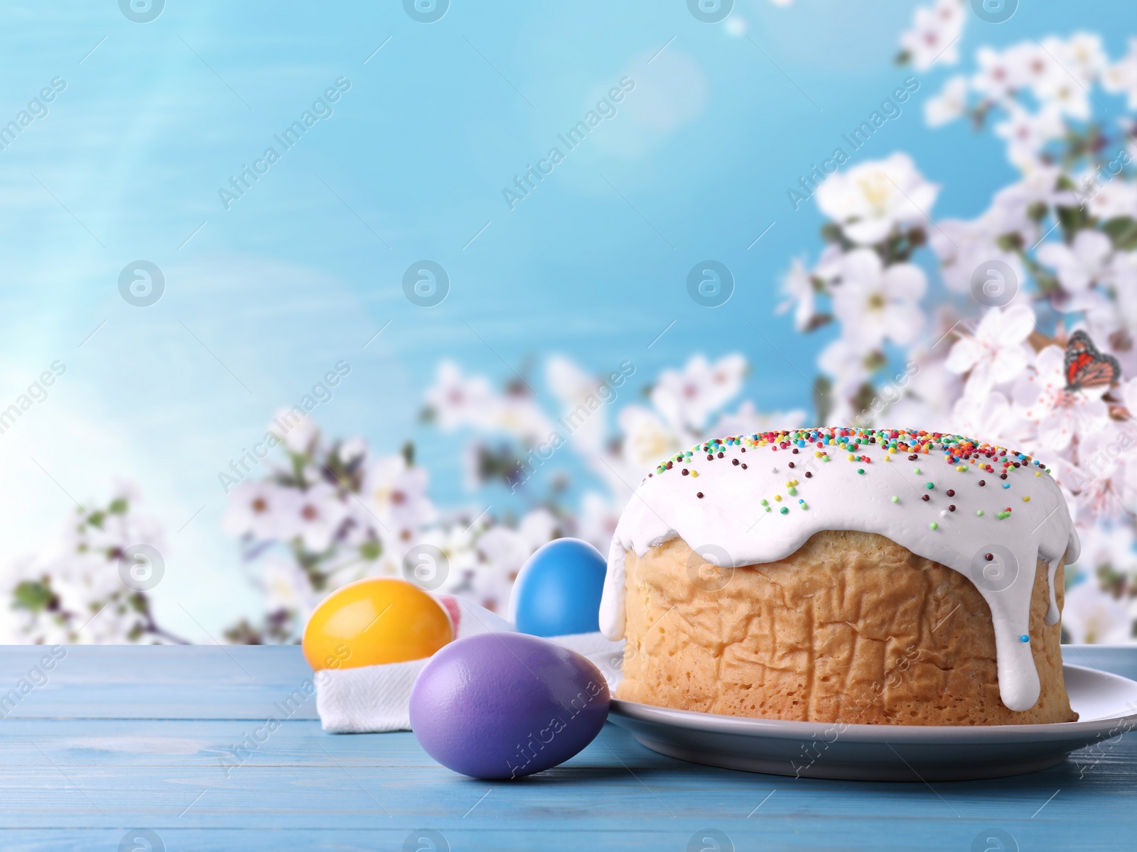Image of Easter cake and dyed eggs on blue wooden table outdoors, space for text