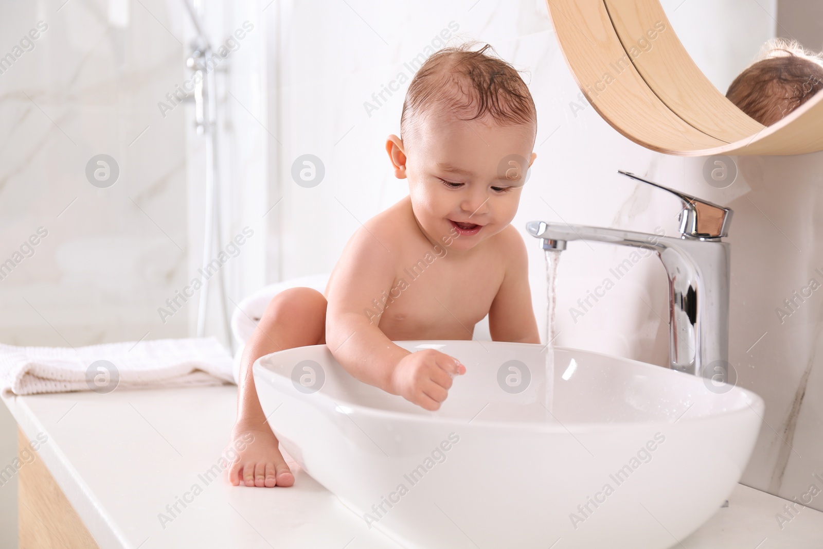 Photo of Cute little baby playing in bathroom at home