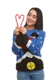Photo of Young woman in Christmas sweater holding candy canes on white background