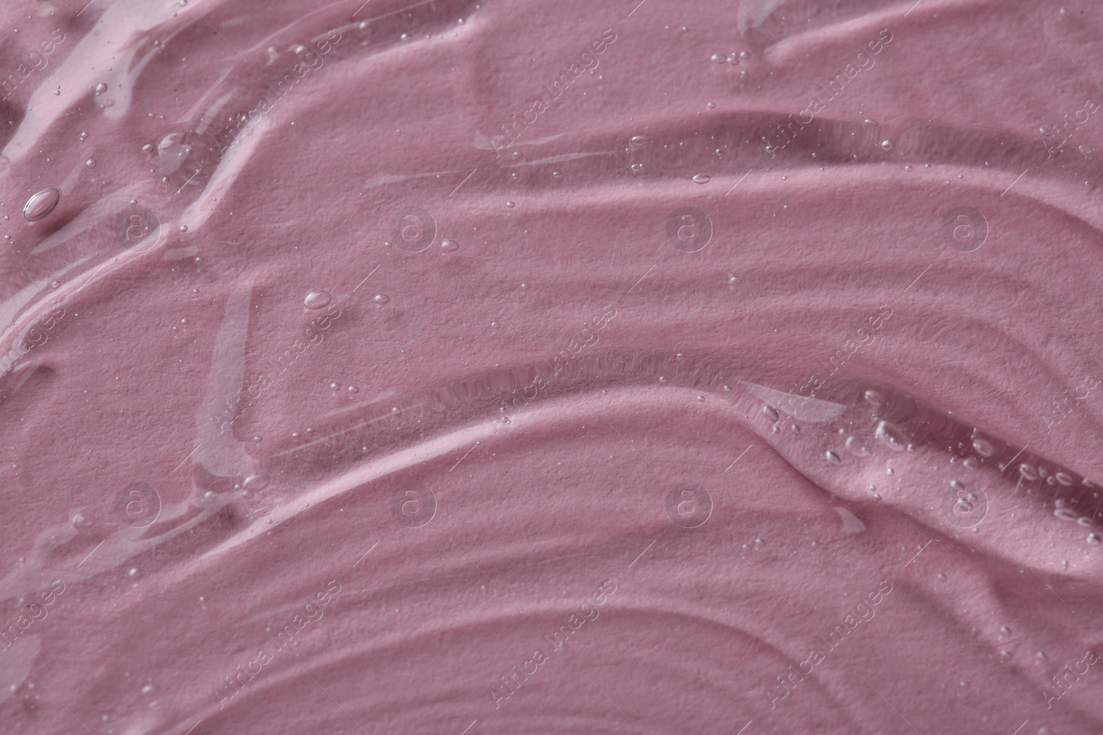 Photo of Clear cosmetic serum on pink background, macro view