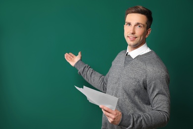 Photo of Portrait of male teacher with papers on color background. Space for text