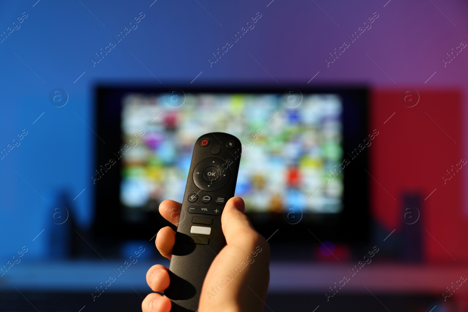 Photo of Woman switching channels on TV set with remote control at home, closeup