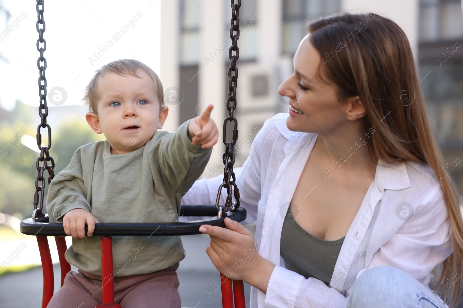 Photo of Happy nanny and cute little boy on swing outdoors