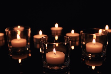 Burning candles in glass holders on dark background